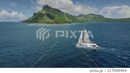 White catamaran sailing near a tropical island in French Polynesia, with lush green vegetation and a beautiful blue sea, offering a breathtaking view of paradise. Amazing nature travel background White catamaran sailing near a tropical island in French Polynesia, with lush green vegetation and a beautiful blue sea, offering a breathtaking view of paradise. Amazing nature travel background 127999464