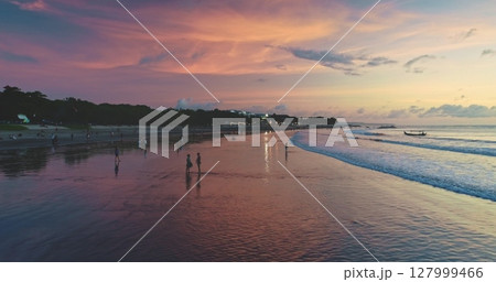 Dreamland Beach in Bali, Indonesia, offers a breathtaking view during sunset, with tourists enjoying the colorful sky and calm ocean waves, creating a serene and picturesque scene 127999466