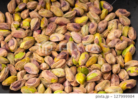 Fried salt pistachio nuts texture background. Baked pistachios grains pattern, pistache fruits Fried salt pistachio nuts texture background. Baked pistachios grains pattern, pistache fruits 127999984