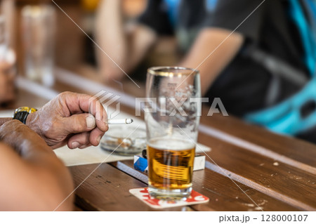 A group of friends are sitting in a pub, smoking cigarettes and drinking beer A group of friends are sitting in a pub, smoking cigarettes and drinking beer 128000107