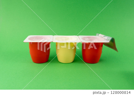 Yogurt cups set, pink and yellow fruit yoghurt in plastic pots, milk pudding container with spoon 128000814