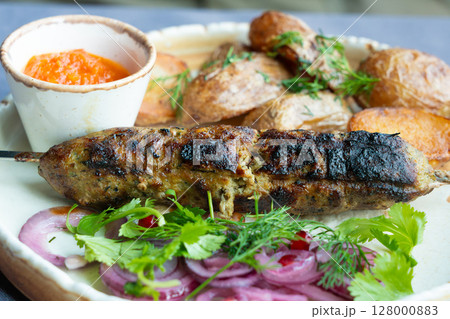 Georgian lula kebab plate. Bbq skewer, traditional barbecue dish with baked potatoes, sauce Georgian lula kebab plate. Bbq skewer, traditional barbecue dish with baked potatoes, sauce 128000883