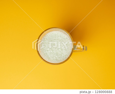 Vanilla milk shake in glass. Milkshake on yellow background, white whey protein smoothie Vanilla milk shake in glass. Milkshake on yellow background, white whey protein smoothie 128000888