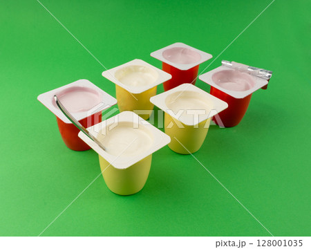Yogurt cups set, pink and yellow fruit yoghurt in plastic pots, milk pudding container with spoon Yogurt cups set, pink and yellow fruit yoghurt in plastic pots, milk pudding container with spoon 128001035
