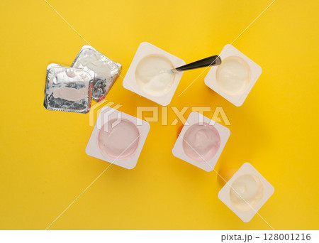 Yogurt cups set, pink and yellow fruit yoghurt in plastic pots, milk pudding container with spoon 128001216