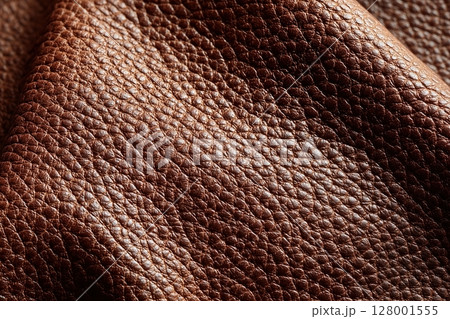 Closeup of warm brown leather texture with rich grain and natural creases 128001555