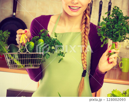 Woman in kitchen having vegetables holding shopping basket Woman in kitchen having vegetables holding shopping basket 128002093