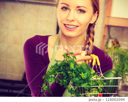 Woman in kitchen having vegetables holding shopping basket 128002094