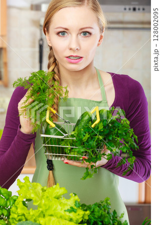 Woman in kitchen having vegetables holding shopping basket Woman in kitchen having vegetables holding shopping basket 128002095