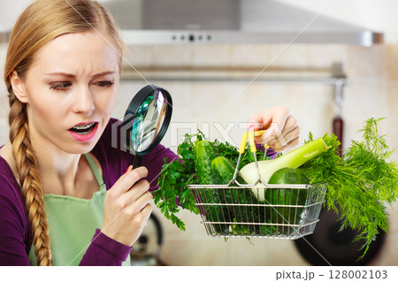 Woman looking through magnifier at vegetables basket 128002103