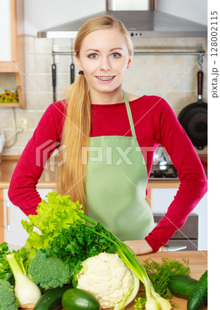 Woman in kitchen having many green vegetables 128002115