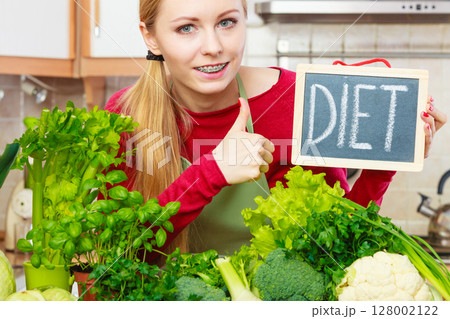 Woman in kitchen having green diet vegetables 128002122