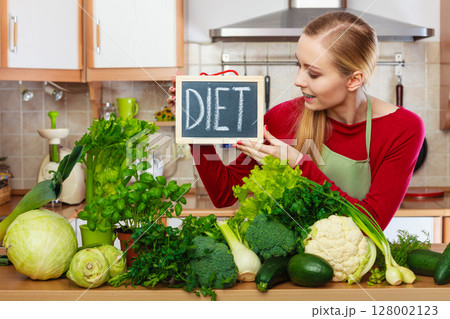 Woman in kitchen having green diet vegetables 128002123