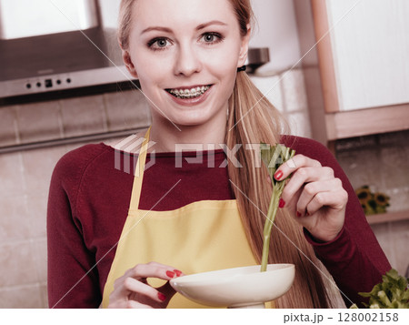 Woman in kitchen making vegetable smoothie juice Woman in kitchen making vegetable smoothie juice 128002158