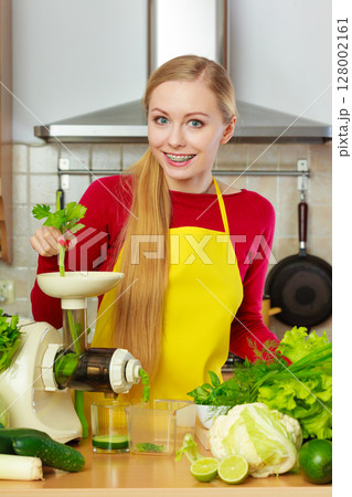 Woman in kitchen making vegetable smoothie juice 128002161
