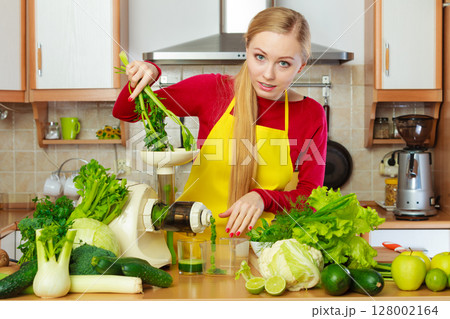 Woman in kitchen making vegetable smoothie juice Woman in kitchen making vegetable smoothie juice 128002164