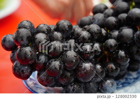 Glossy Black Grapes in Close-Up with Water Droplets 128002330