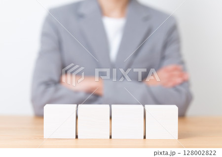 グレースーツを着て悩むミドル女性と無地のブロック 128002822