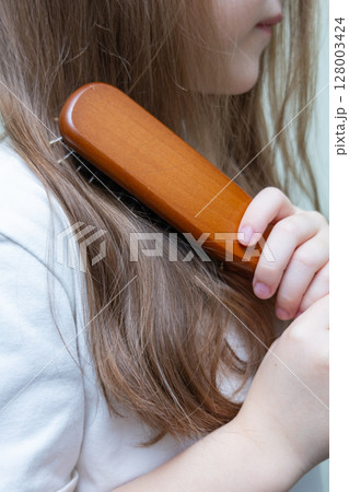 Young woman with long, dark blonde hair pulled back in a low ponytail. Casual hairstyle. Sporty hairstyle. Running hairstyle. 128003424