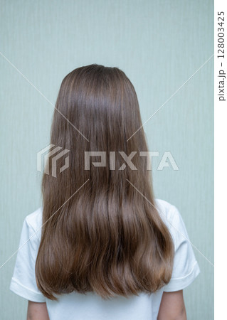 Rear view of little girl in floral dress looking at wall. Isolated on white background 128003425