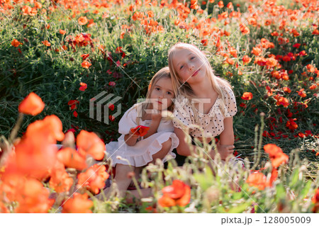 Sisters on plaid in a blooming poppy field, sunny summer day Sisters on plaid in a blooming poppy field, sunny summer day 128005009