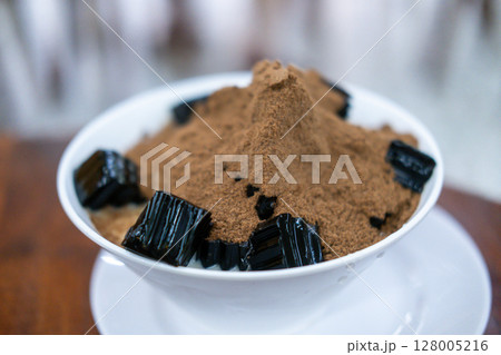 Grass jelly with fresh milk and chocolate powder, served in a bowl. Thai dessert 128005216