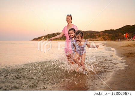 Joyful family moments splashing near the shore at sunset Joyful family moments splashing near the shore at sunset 128006675