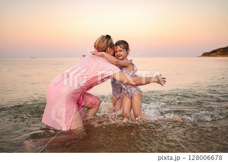 Joyful family moments at the beach during sunset 128006678