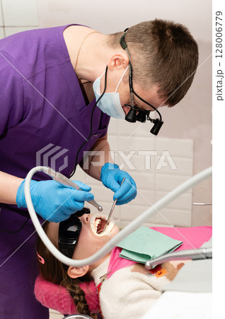 Young patient receiving dental care from a professional in a modern clinic with a bright atmosphere focused on oral health and comfort 128006779