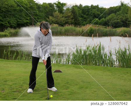 Golf Practice Session by the Serene Pond in a Lush Park Setting Golf Practice Session by the Serene Pond in a Lush Park Setting 128007042