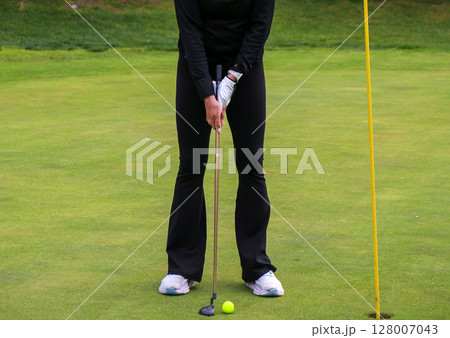 Golfer Prepares to Putt on a Lush Green Golf Course Golfer Prepares to Putt on a Lush Green Golf Course 128007043