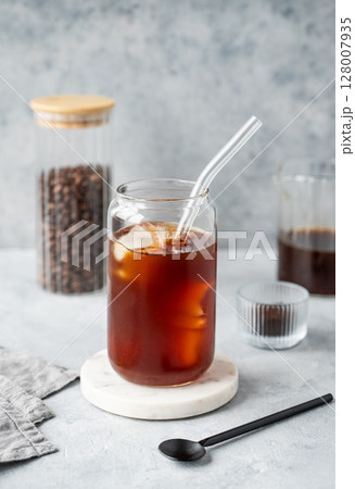 Cold brew coffee in a glass with ice on a marble stand on a light concrete background Cold brew coffee in a glass with ice on a marble stand on a light concrete background 128007935