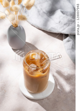 Ice latte coffee in a glass with milk on a light background with dry bouquet flowers Ice latte coffee in a glass with milk on a light background with dry bouquet flowers 128007948