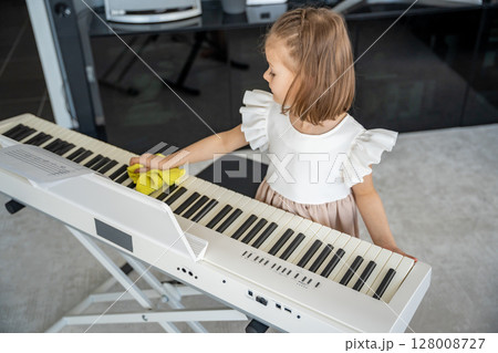 Little girl carefully cleaning her piano at home in the living room. Early childhood education through music includes care, responsibility and respect for the instrument. Little girl carefully cleaning her piano at home in the living room. Early childhood education through music includes care, responsibility and respect for the instrument. 128008727