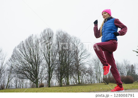 Woman wearing sportswear exercising outside during autumn 128008791