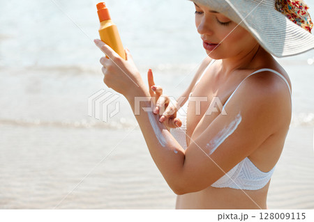 Woman Applying Sun Cream on Tanned Skin. Sun Protection. Skin Care. Girl Smears Sunscreen on Skin. Portrait of Female Holding Suntan Lotion or Moisturizing Sunblock 128009115