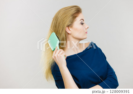 Woman brushing her long hair with brush 128009391