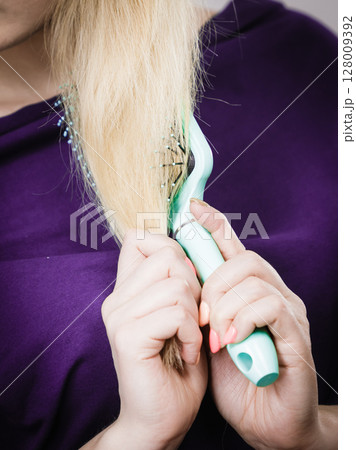 Unrecognizable blonde woman brushing hair 128009392