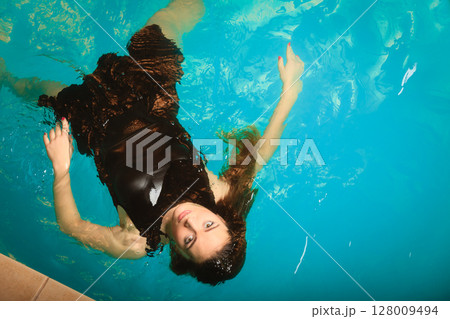 Woman floating relaxing in swimming pool water. 128009494