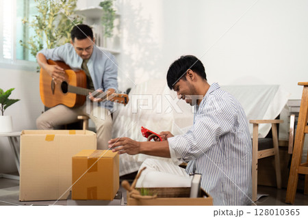 Gay couple enjoying music and unpacking in their new home Gay couple enjoying music and unpacking in their new home 128010365