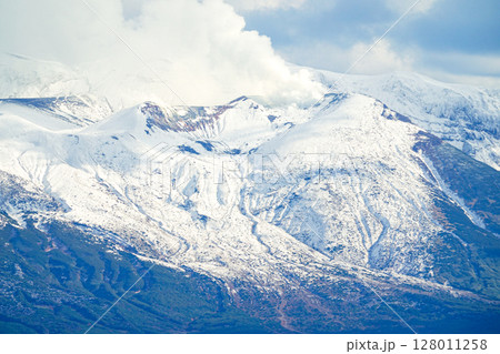 噴煙をあげる冠雪した北海道十勝岳連峰 128011258