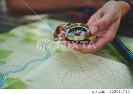 Traveler Holding a Compass Over a Map Highlights Navigation and Exploration 128011730