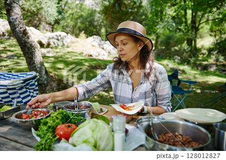 Woman Prepares Food Outdoors at a Scenic Picnic Spot in Nature 128012827