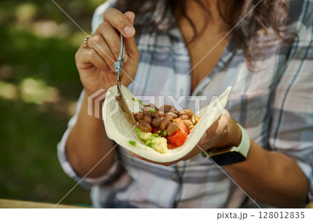 A Close-Up of a Woman Holding and Filling a Fresh Bean Vegan Wrap 128012835