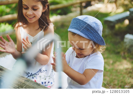 Two Young Children Enjoying a Moment of Play Outdoors in a Natural Park Setting Two Young Children Enjoying a Moment of Play Outdoors in a Natural Park Setting 128013105