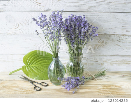 Bouquet of lavender flowers in a glass vase on a wooden background. Floral still life. Bouquet of lavender flowers in a glass vase on a wooden background. Floral still life. 128014286