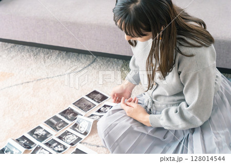 エコー写真を見て赤ちゃんが生まれてくるのを楽しみにしている妊婦 エコー写真を見て赤ちゃんが生まれてくるのを楽しみにしている妊婦 128014544
