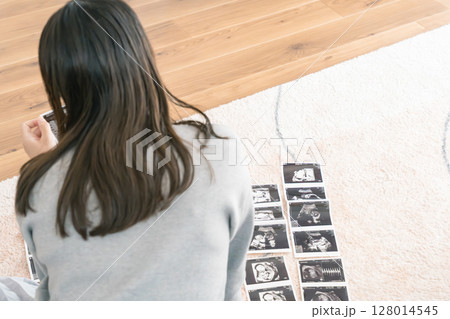 エコー写真を見て赤ちゃんが生まれてくるのを楽しみにしている妊婦 エコー写真を見て赤ちゃんが生まれてくるのを楽しみにしている妊婦 128014545