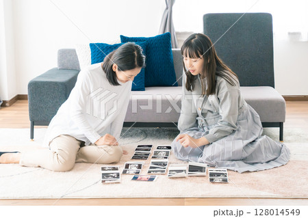 エコー写真を見ながら、赤ちゃんが生まれてくるのが待ち遠しい母と娘 エコー写真を見ながら、赤ちゃんが生まれてくるのが待ち遠しい母と娘 128014549