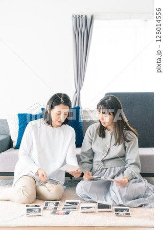 エコー写真を見ながら、赤ちゃんが生まれてくるのが待ち遠しい母と娘 128014556